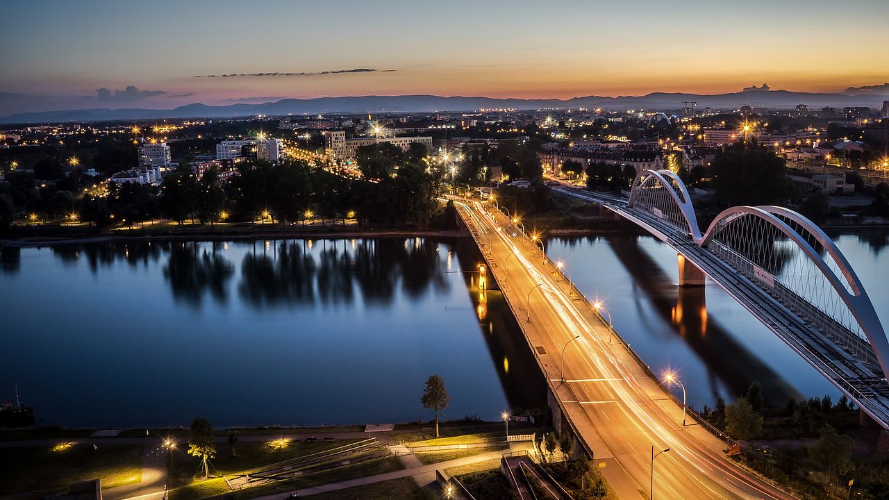 Blick von Kehl über den Rhein nach Straßburg mit der Europabrücke und Fußgängerbrücke im Abendlicht.