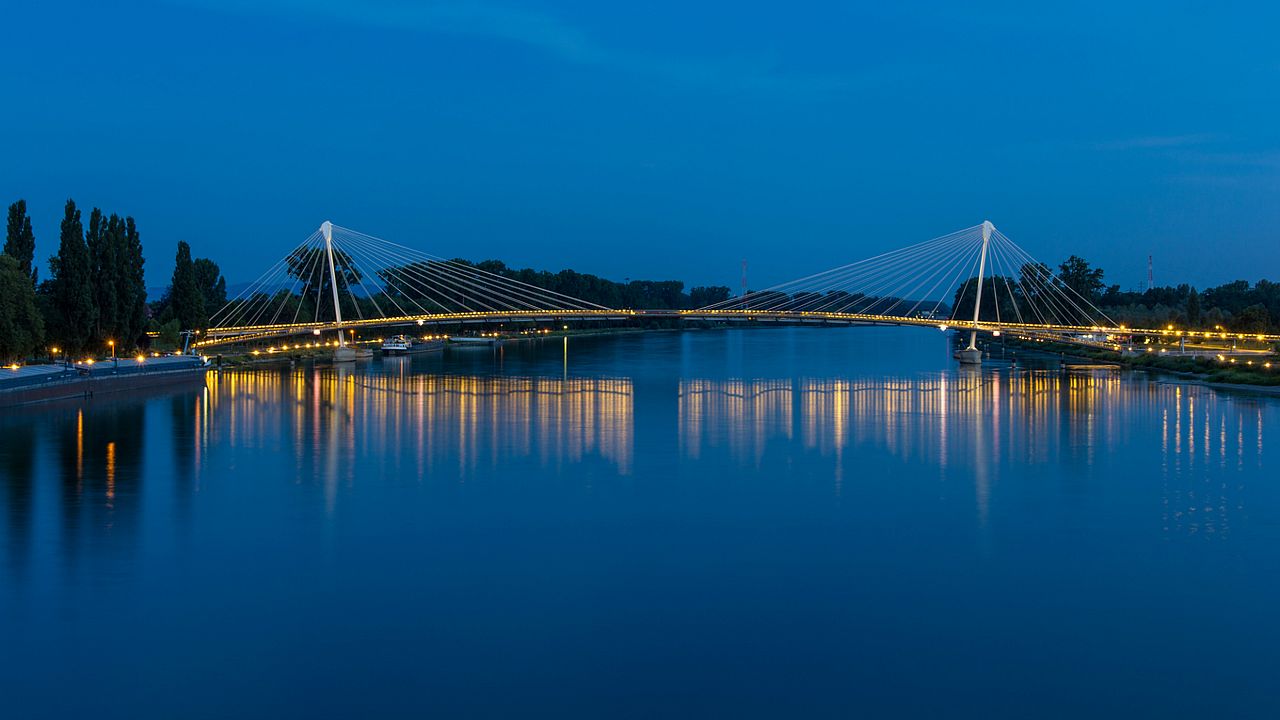 Abendlich beleuchtete Brücke über einen breiten Fluss